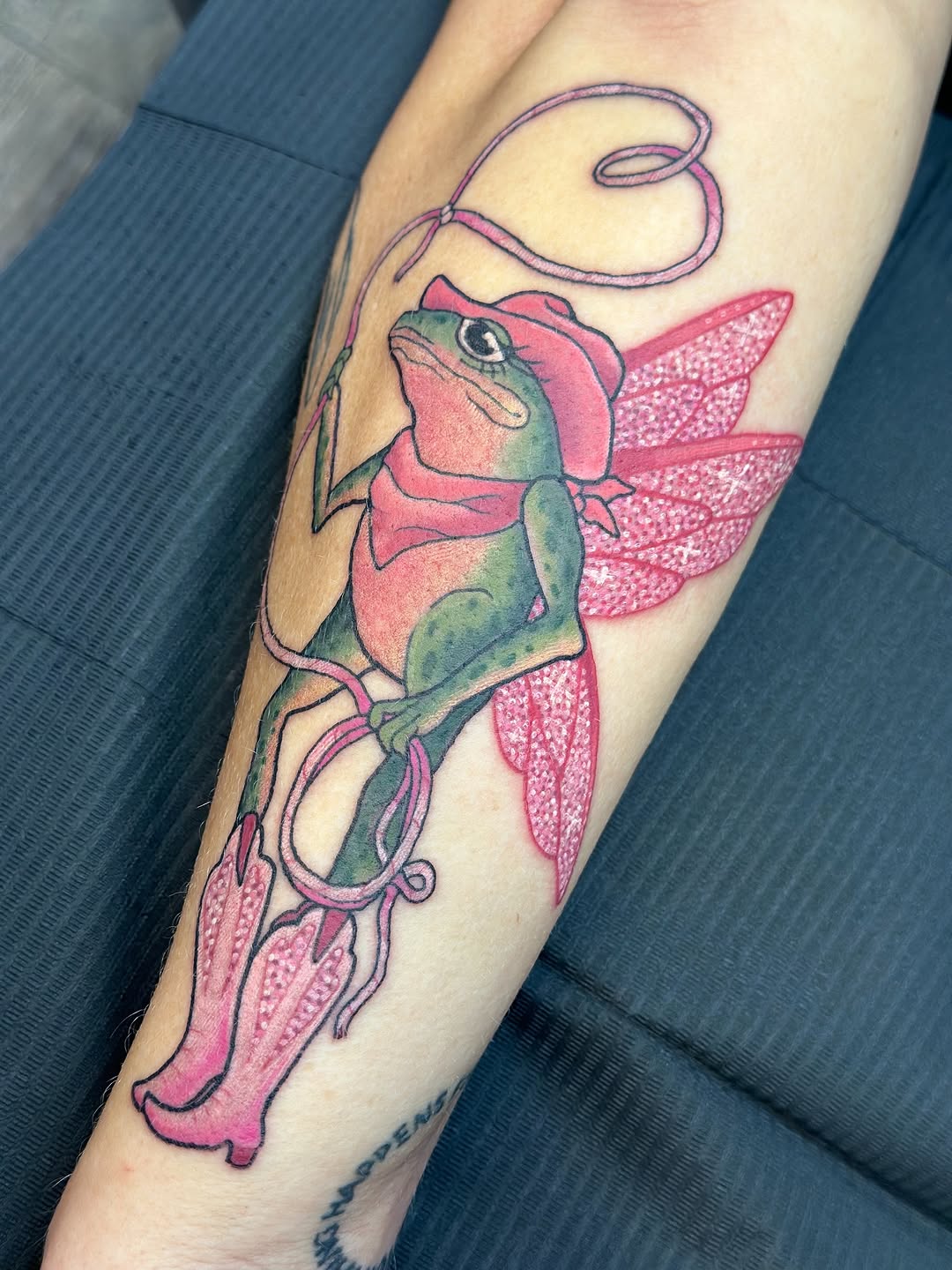 Vibrant fantasy frog with pink wings and looping ribbon