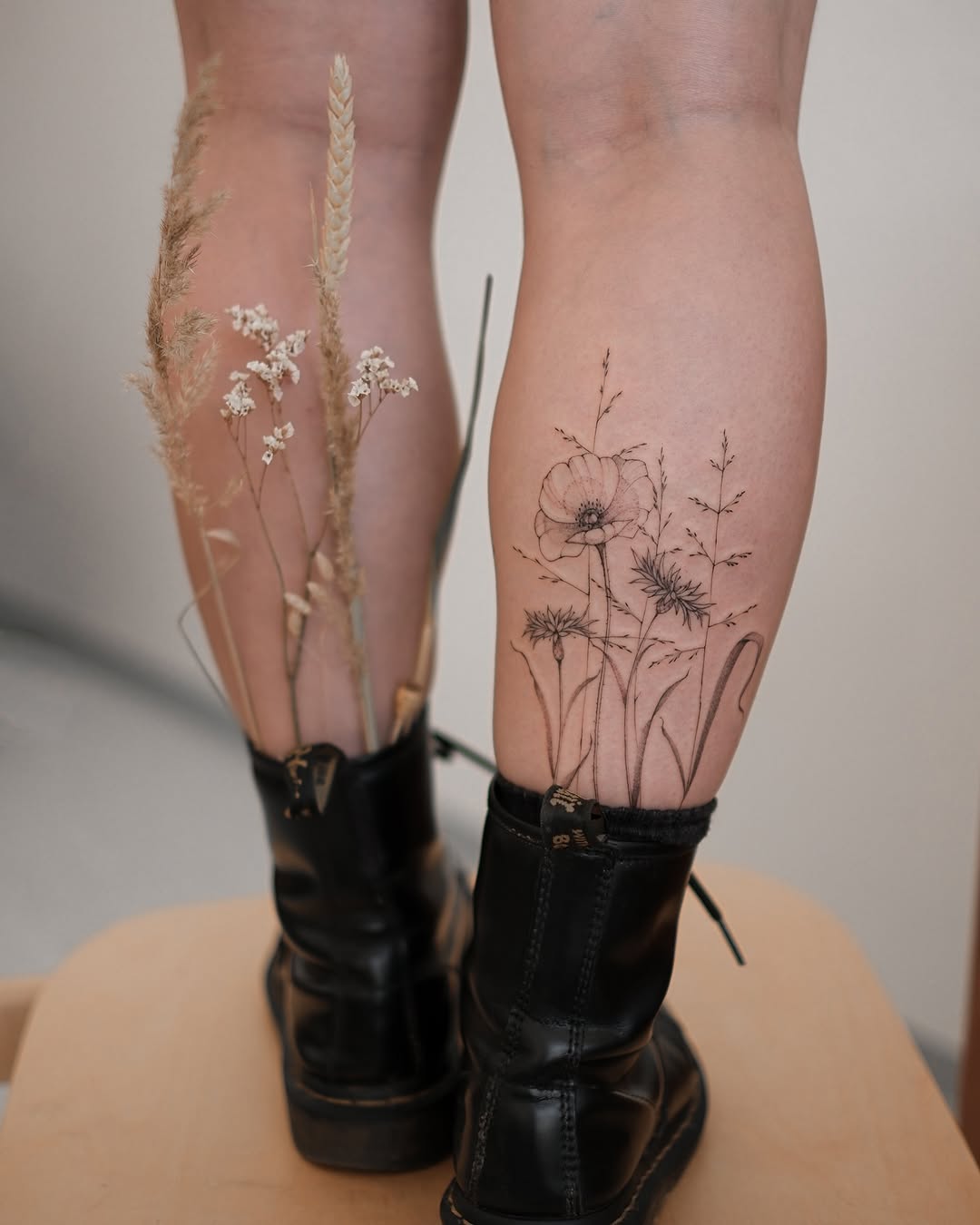 Delicate fineline botanical calf tattoo featuring poppy