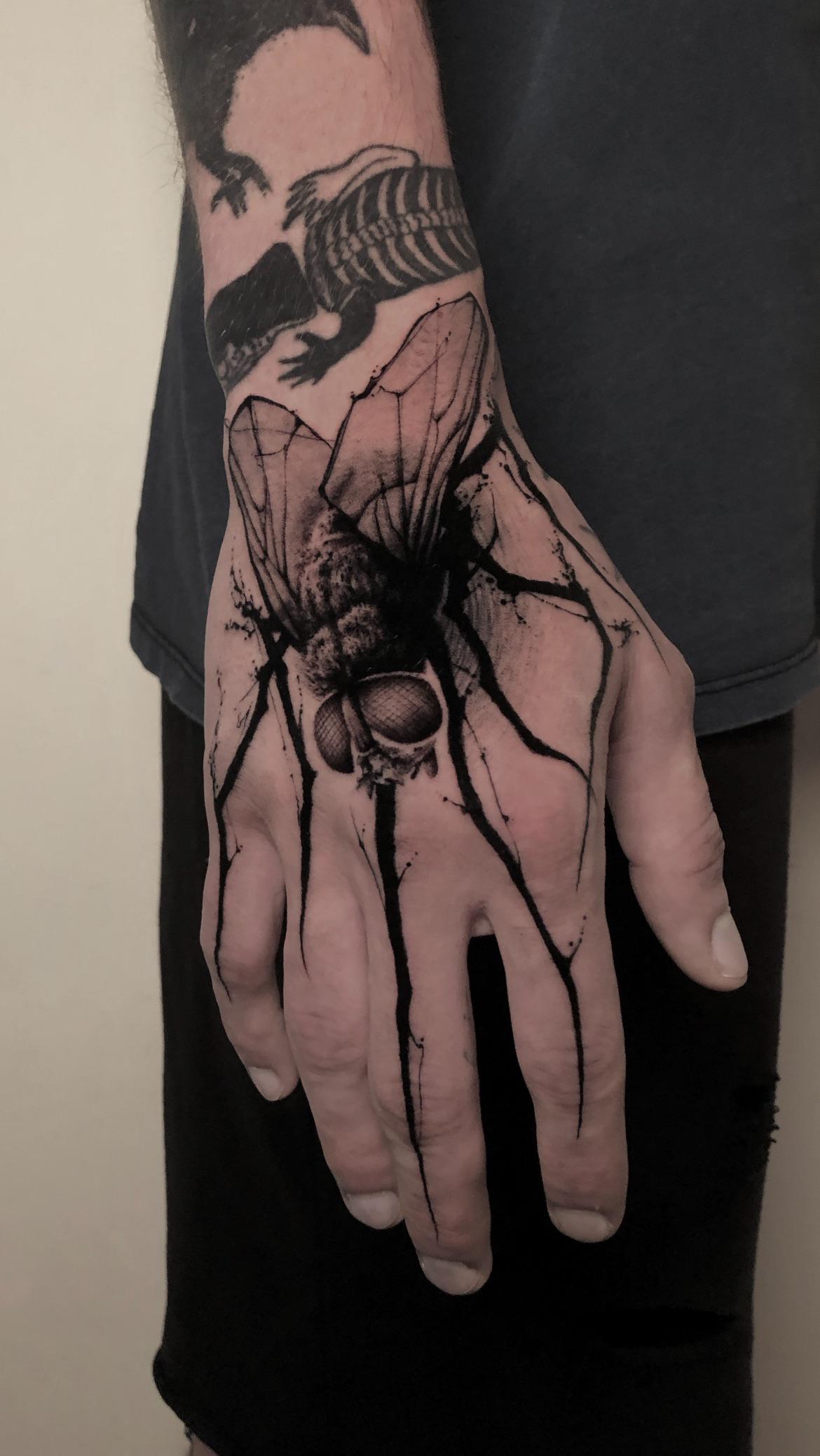 Bold blackwork hand piece featuring a spider-like insect and fractured orb.