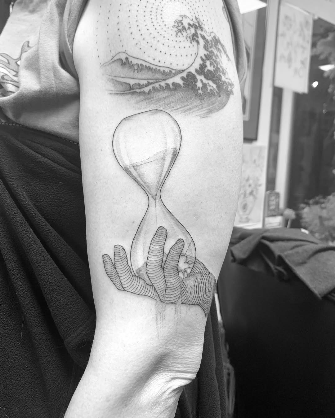 Bold linework hourglass cradled by ribbed, stylized hand