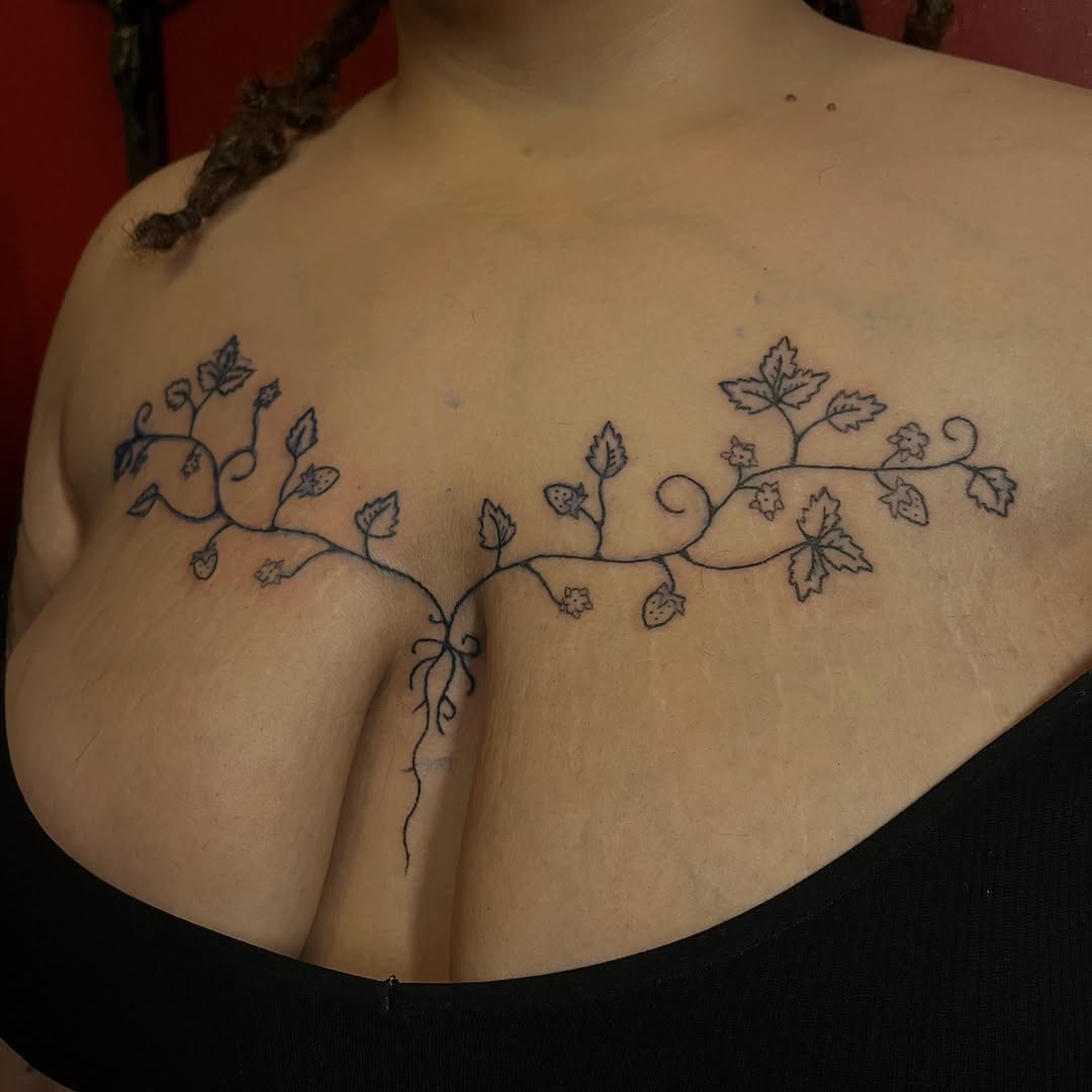 Delicate hand-poked strawberry vine across the chest
