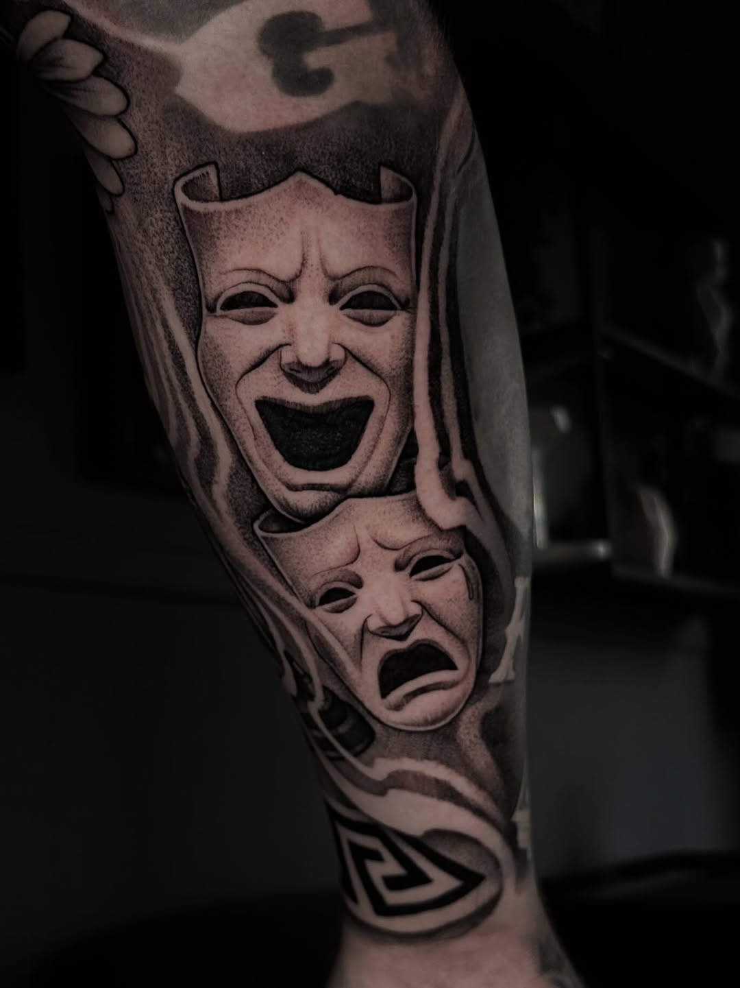 Monumental black-and-gray comedy and tragedy masks with dramatic shading