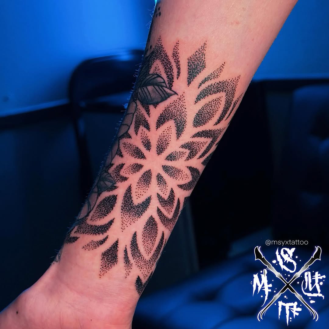 Intricate dotwork mandala pattern with petal-like arcs on forearm
