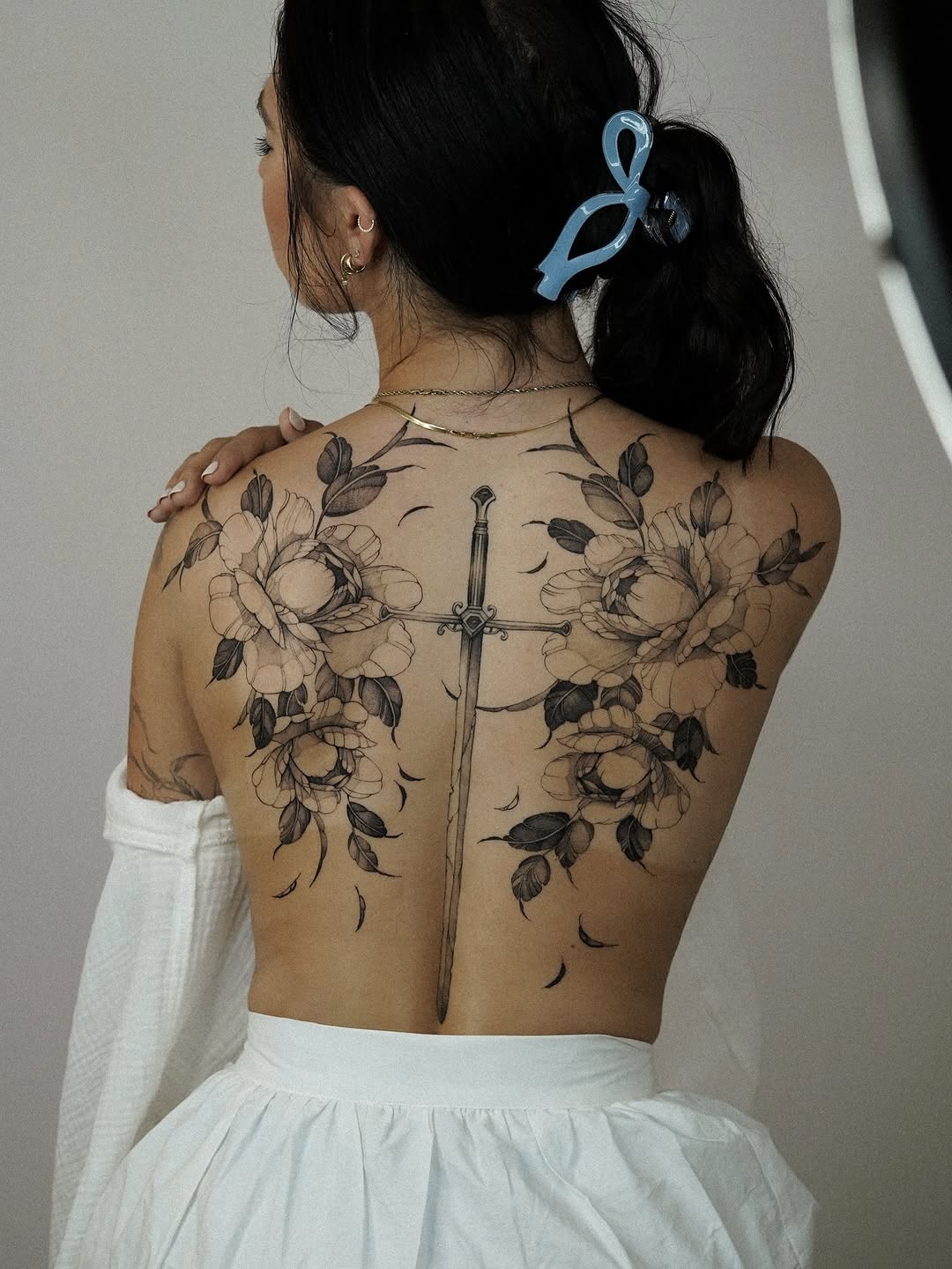 Intricate black-and-gray back piece featuring sword and peonies