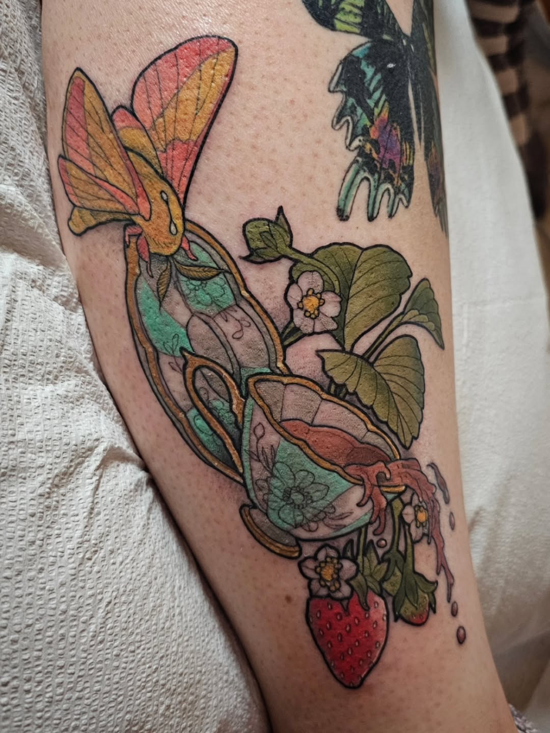Bold neo-traditional botanical tattoo featuring strawberry and blooms.