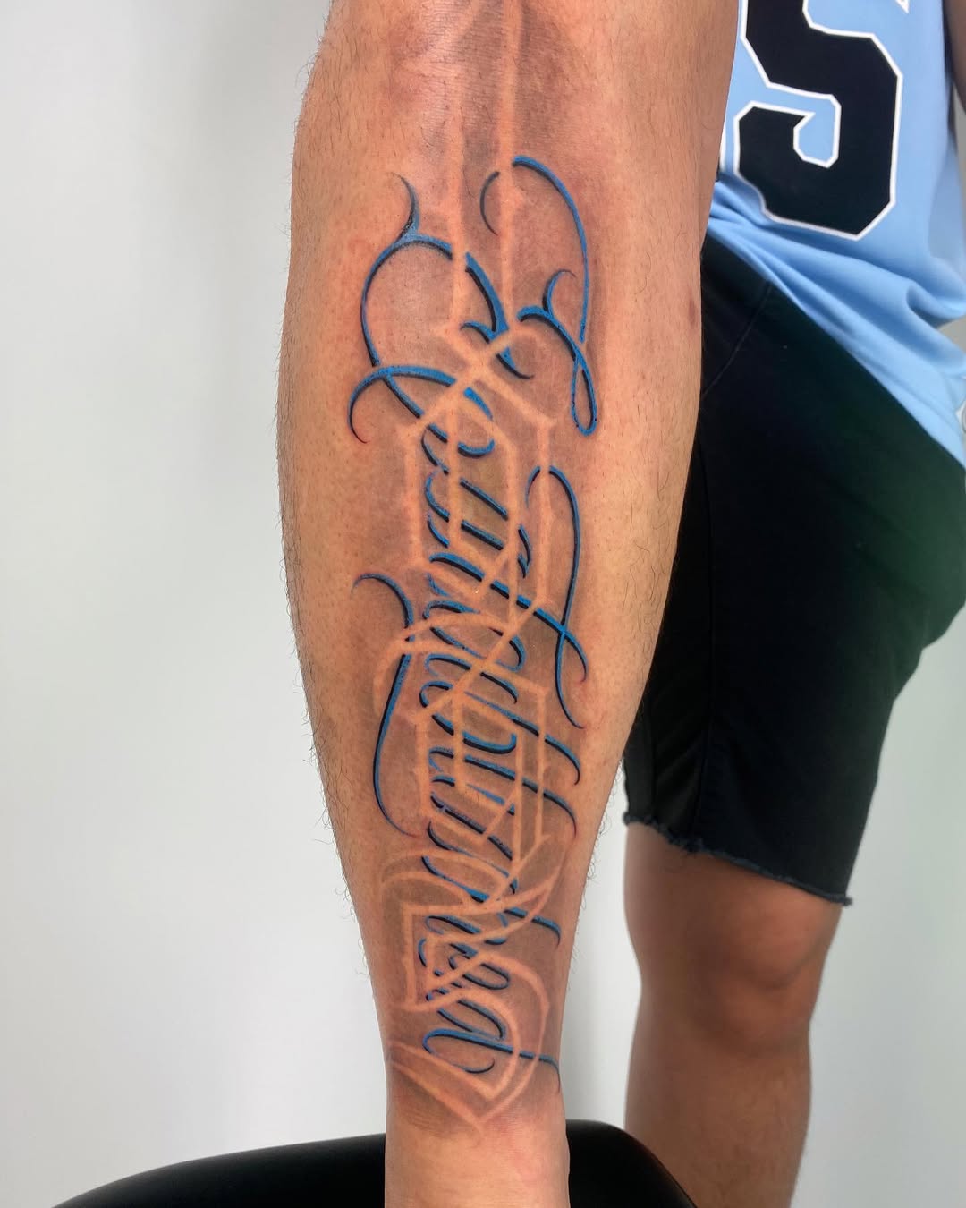 Intricate blue-outlined calligraphic script leg sleeve