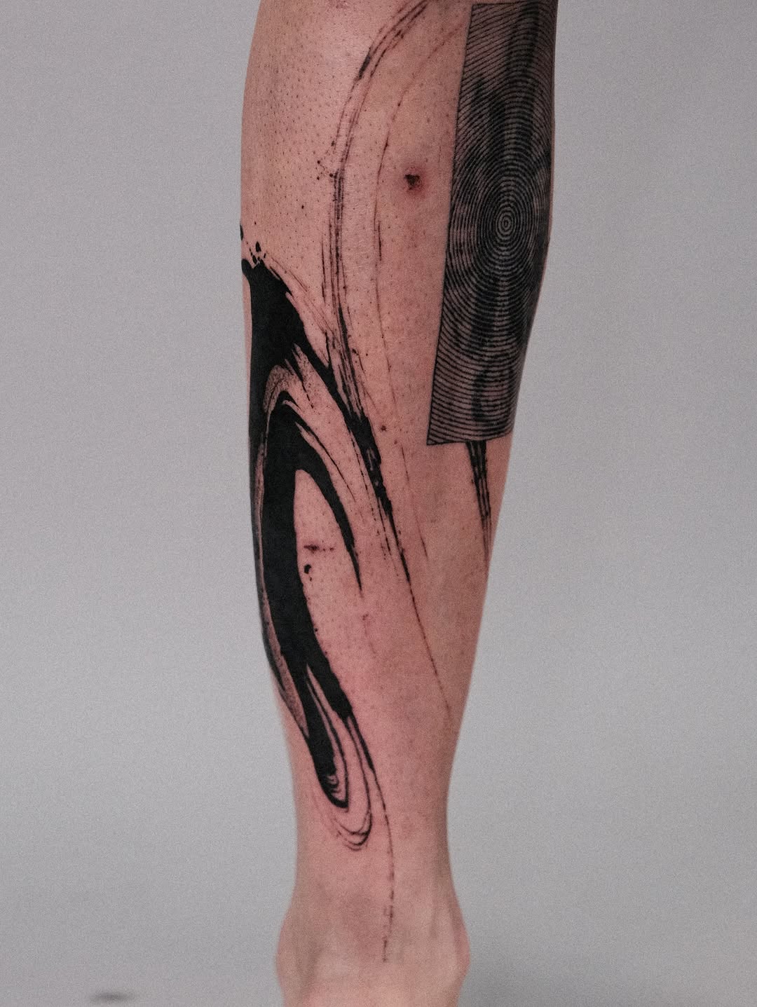 Bold black abstract brushstroke on forearm.