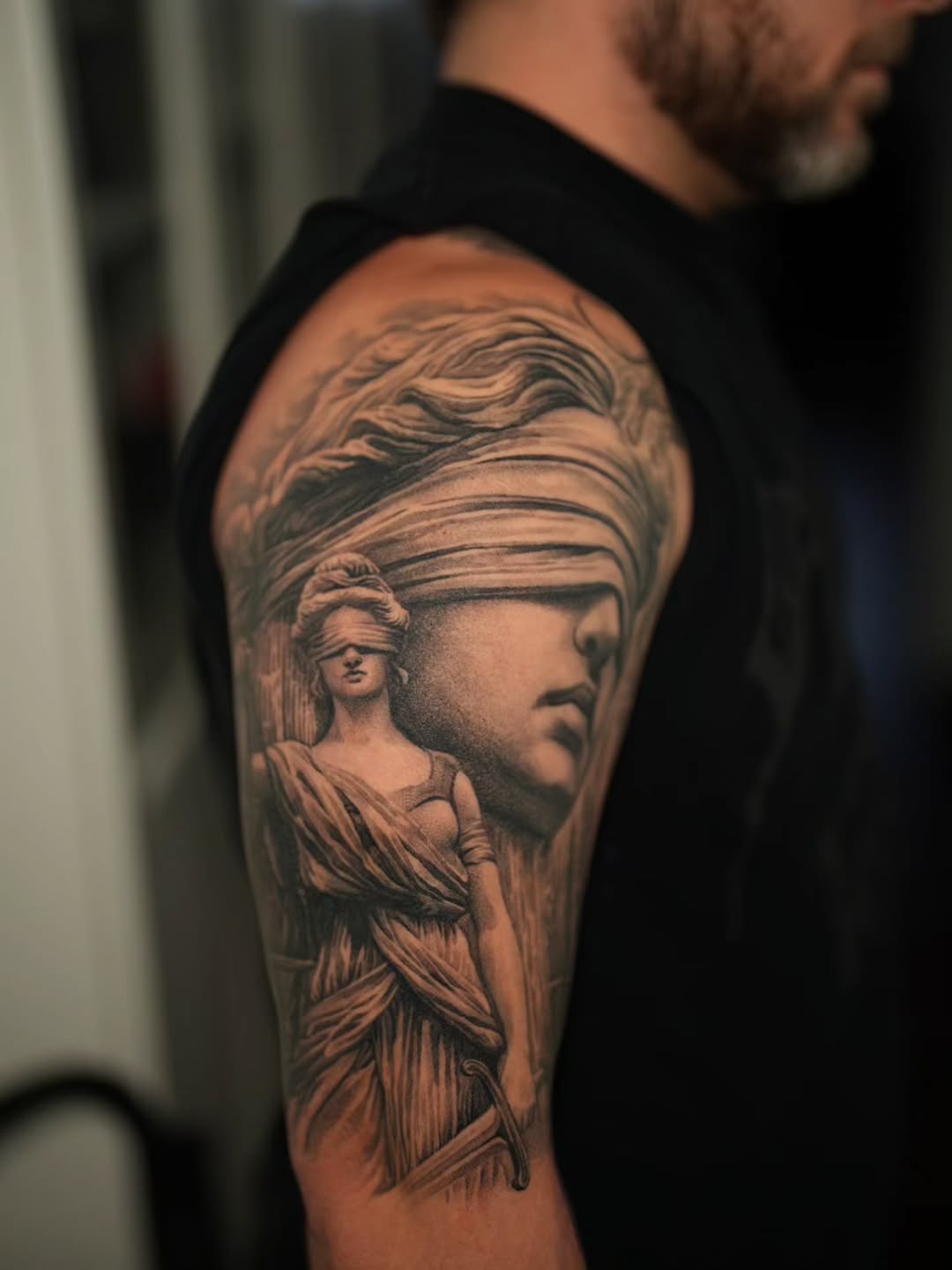 Classical, blindfolded Lady Justice statue in grayscale