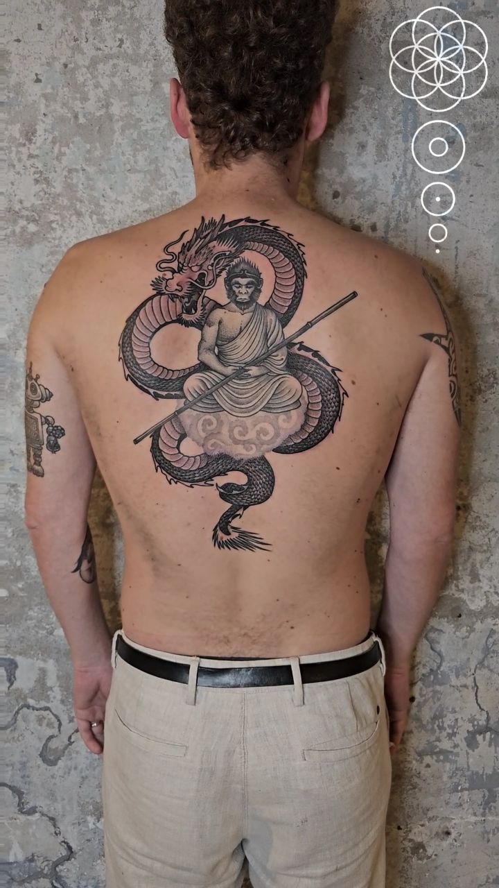 Monumental blackwork dragon coils around a meditating sage