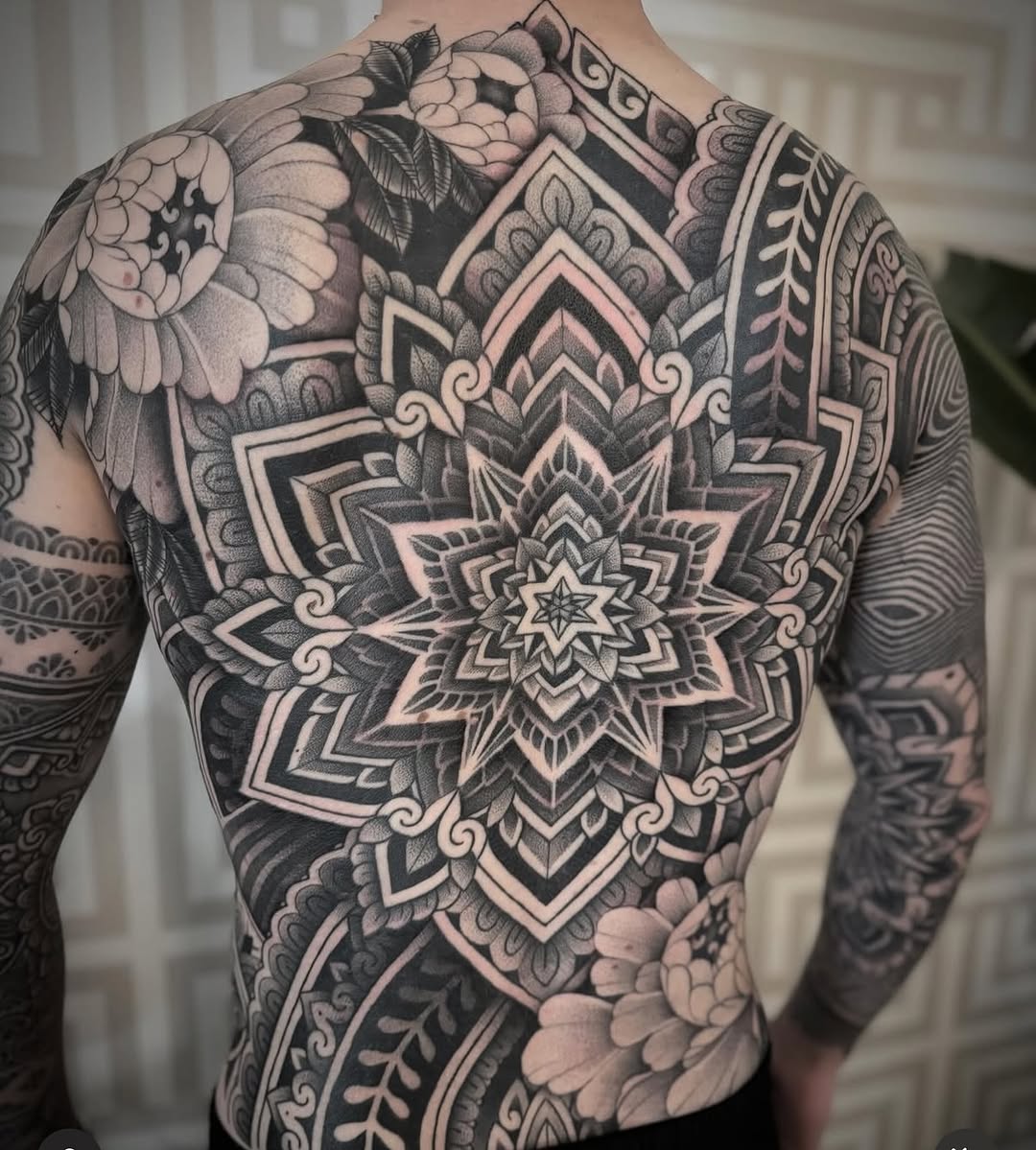 Intricate blackwork mandala back-piece with sweeping floral accents.