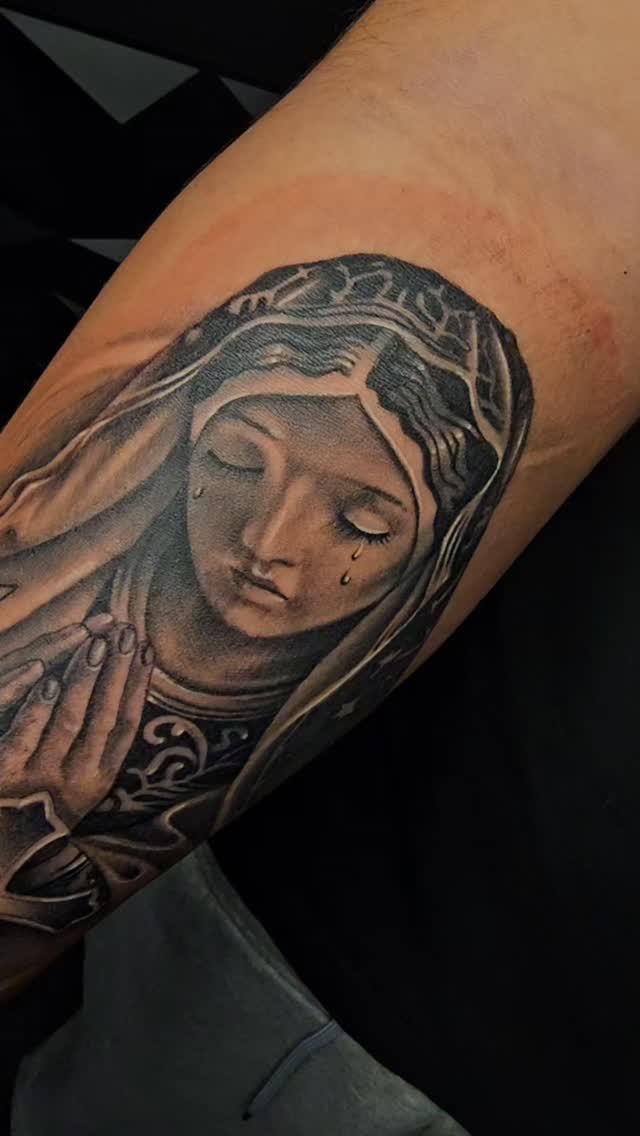 Realistic black-and-gray Virgin Mary portrait with teardrops