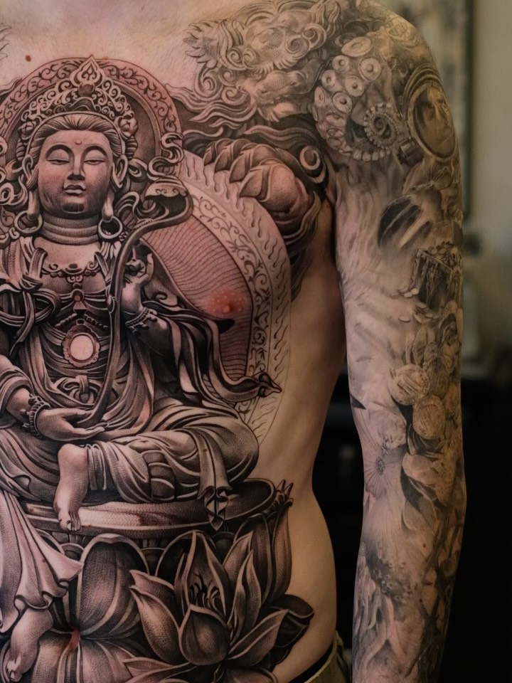Monumental black-and-gray Buddha on chest with detailed sleeve.