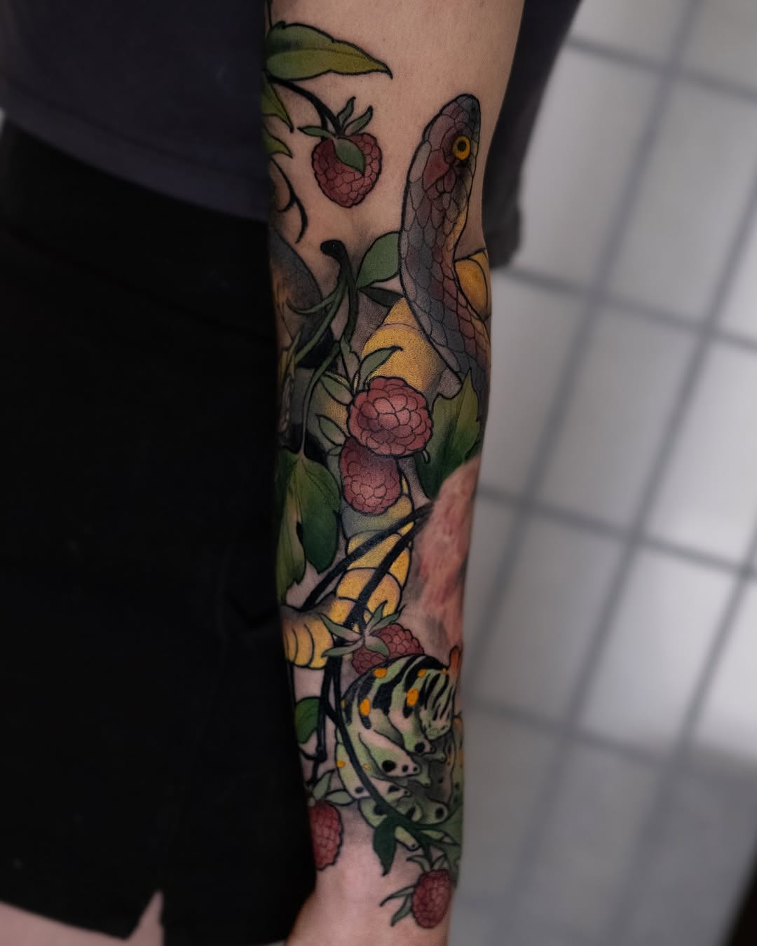 Vibrant neo-traditional forearm snake among berries
