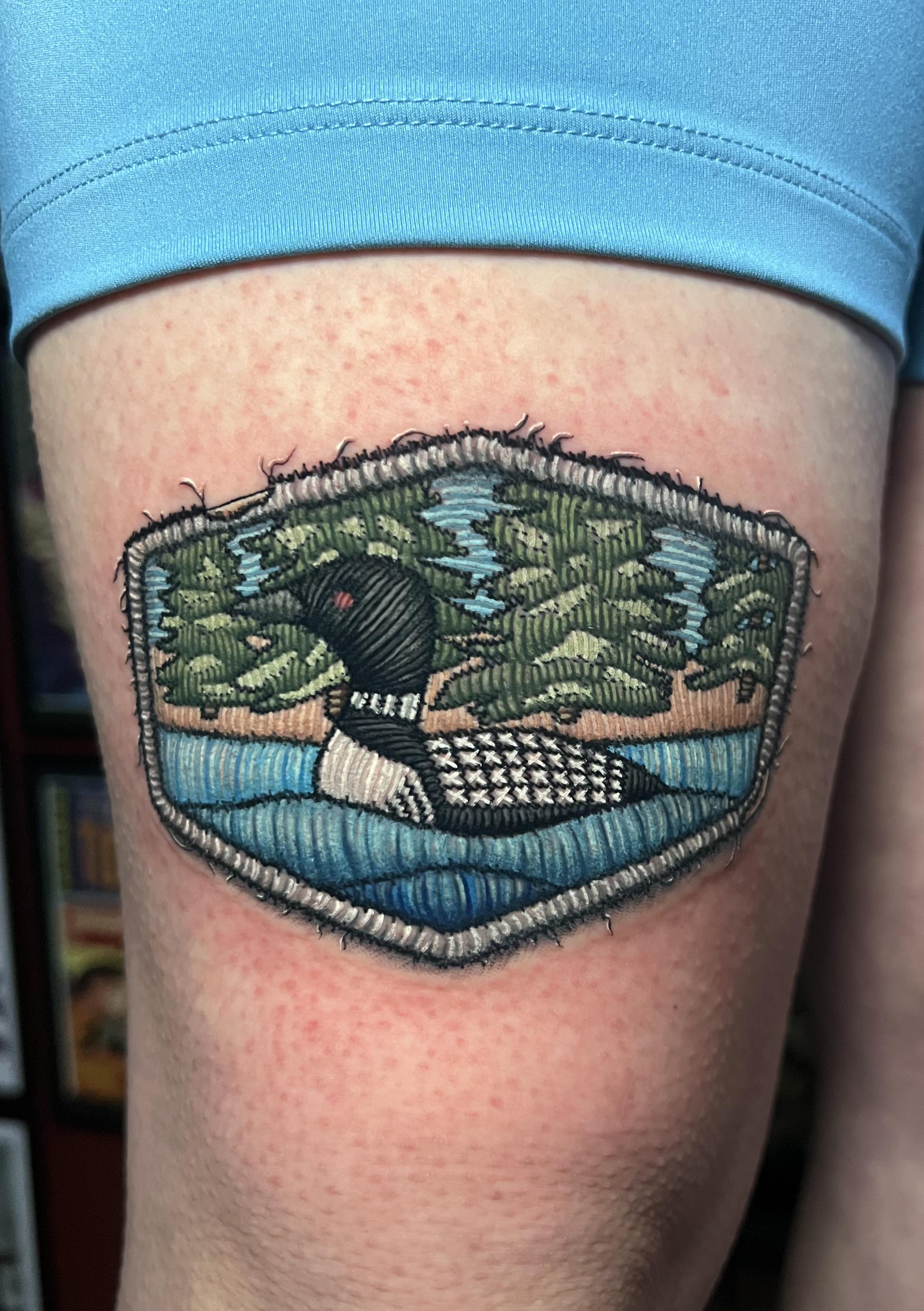 Patch-style loon amid pines over a blue lake