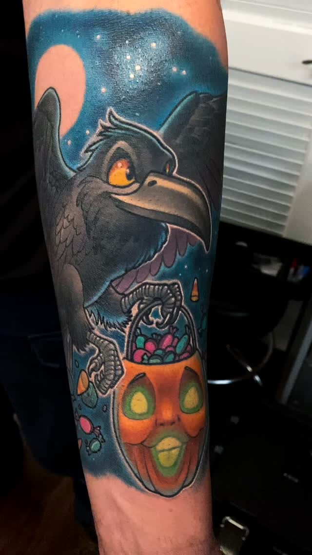 Vivid neon raven beside a candy-filled jack-o'-lantern.