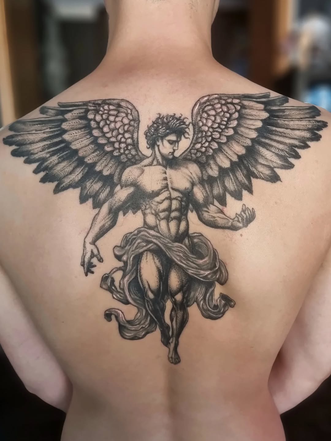 Monumental black-and-gray angel with sprawling detailed wings.