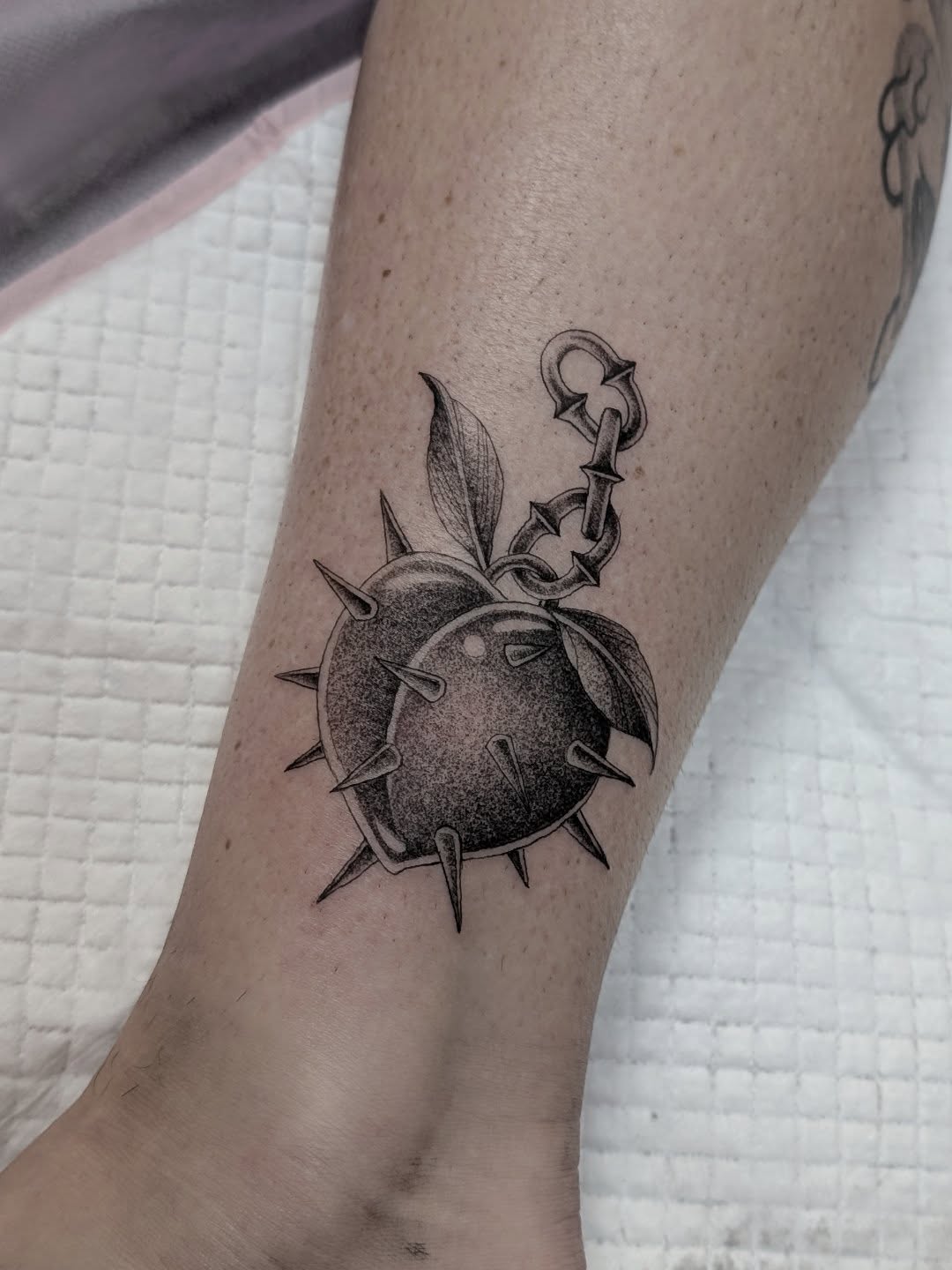Spiked thorn ball with leaves, chain accent, stippled shading.