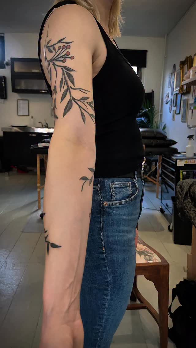 Elegant botanical vine coils along arm with crisp leaves.