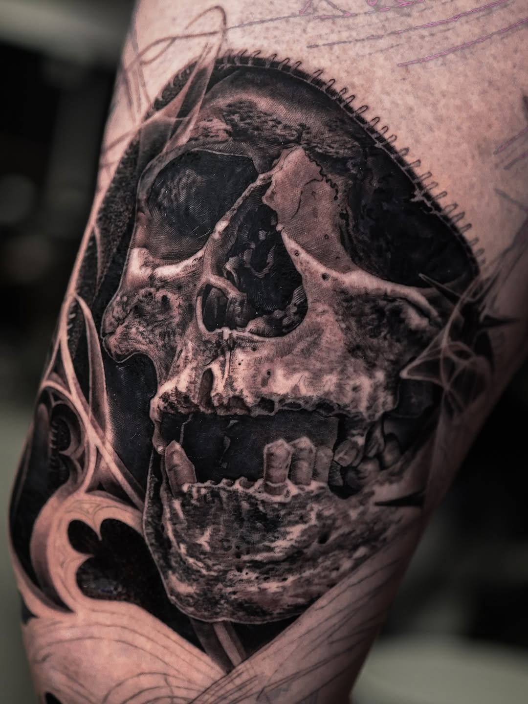 Hyper-detailed grayscale skull on leg with ornamental motifs.