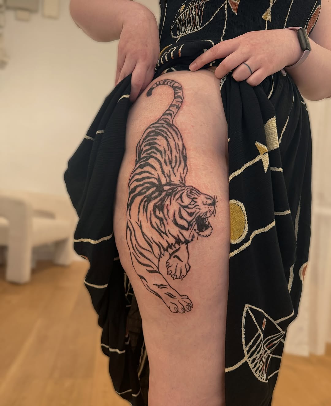 Dynamic bold tiger in mid-leap on thigh, fierce linework