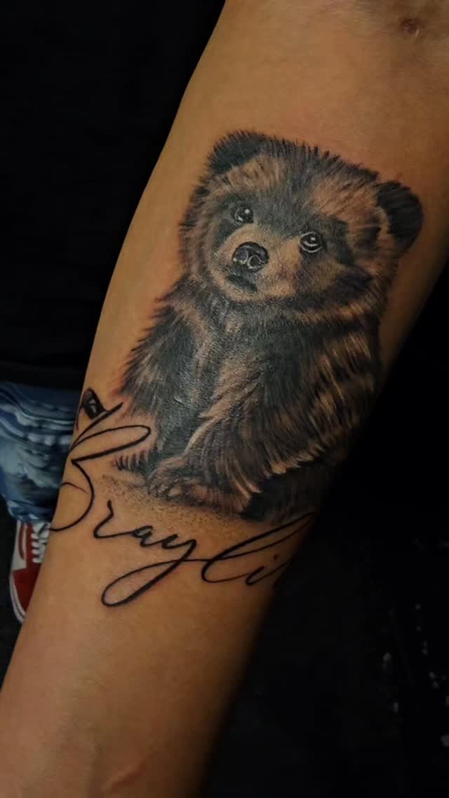Cute black-and-gray bear cub with flowing script.