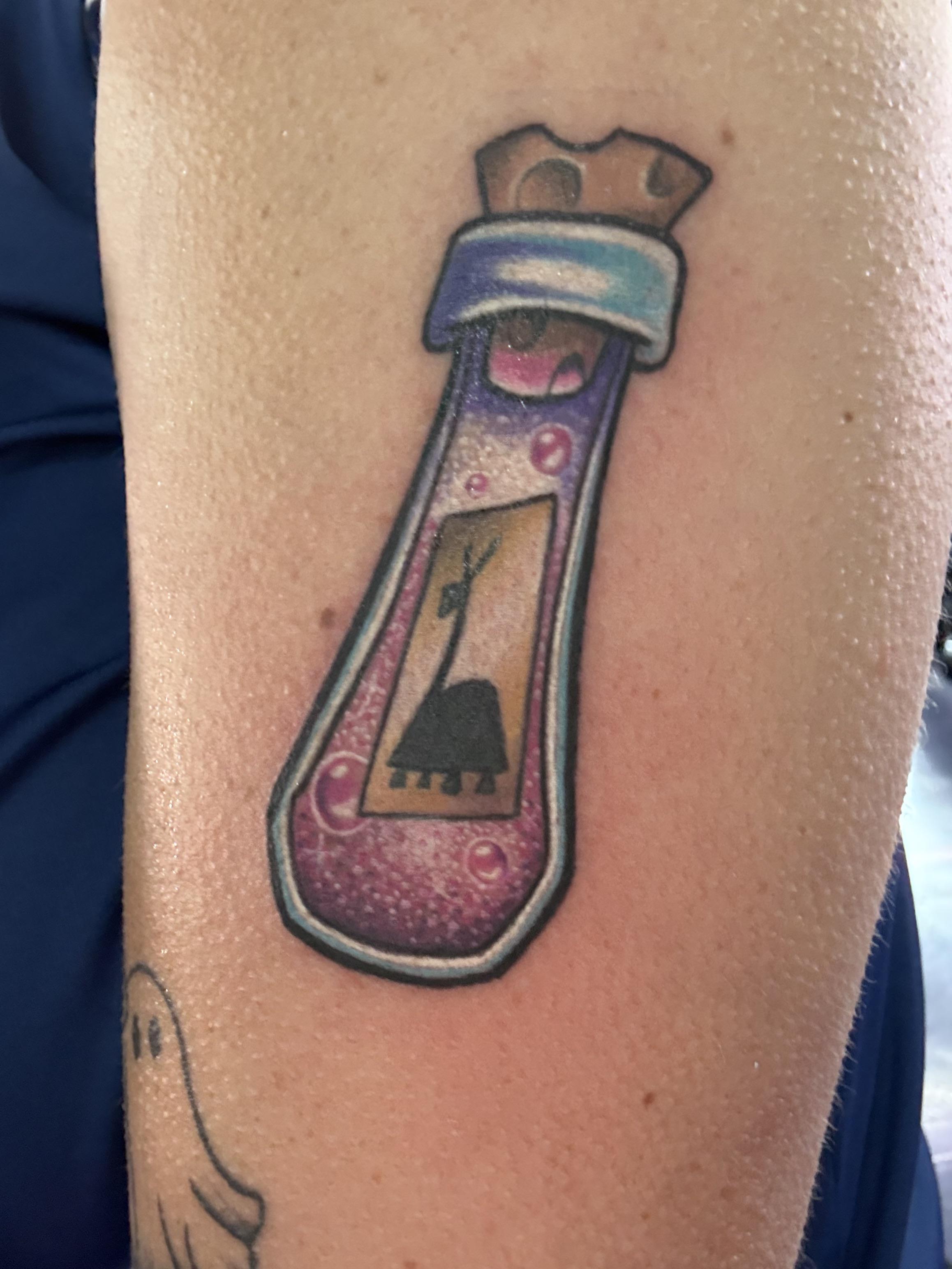 Whimsical bottle tattoo with pink liquid and quirky label.
