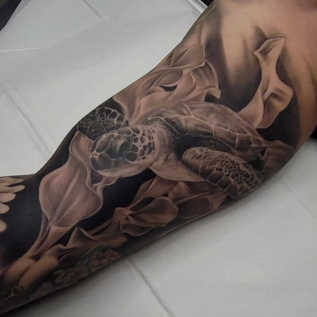 Hyper-detailed black-and-gray sea turtle swimming sleeve.