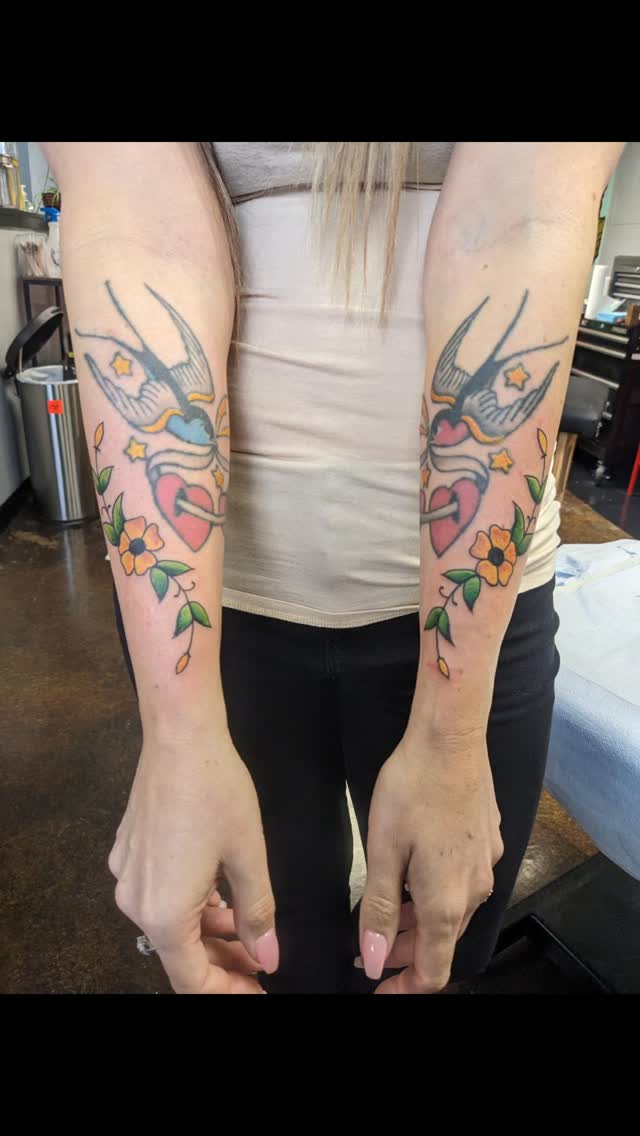 Bold traditional swallows framed by vivid flowers and vines