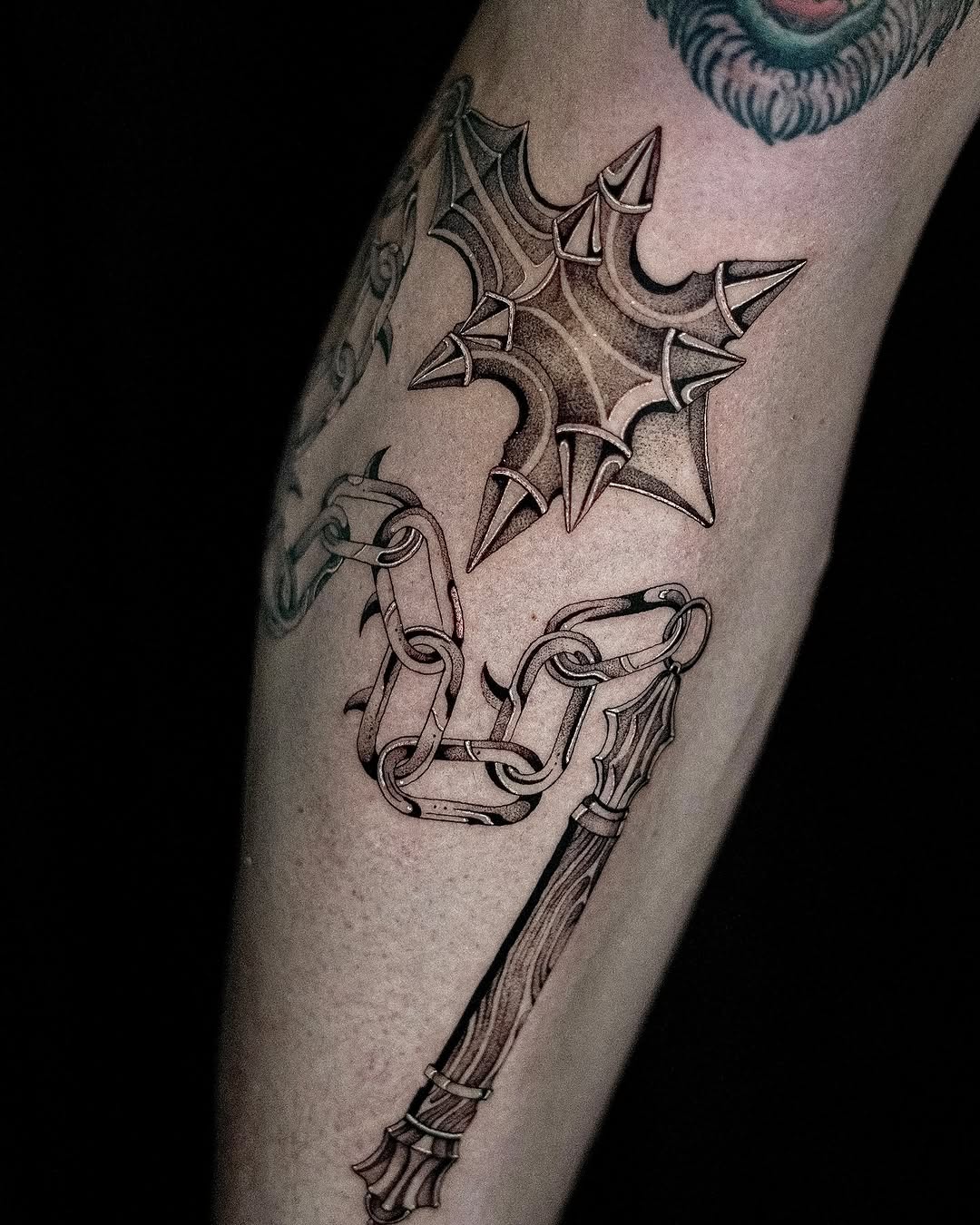 Angular spiky cross motif above chained mace in blackwork