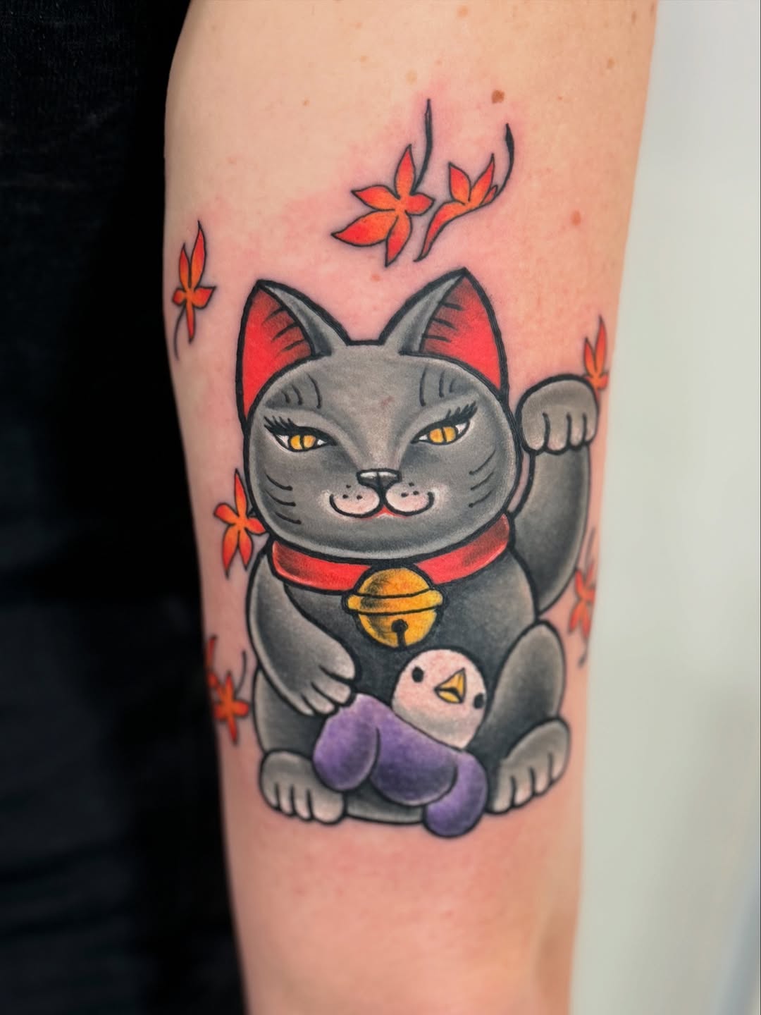 Bold Japanese maneki-neko cat with gold bell holding chick