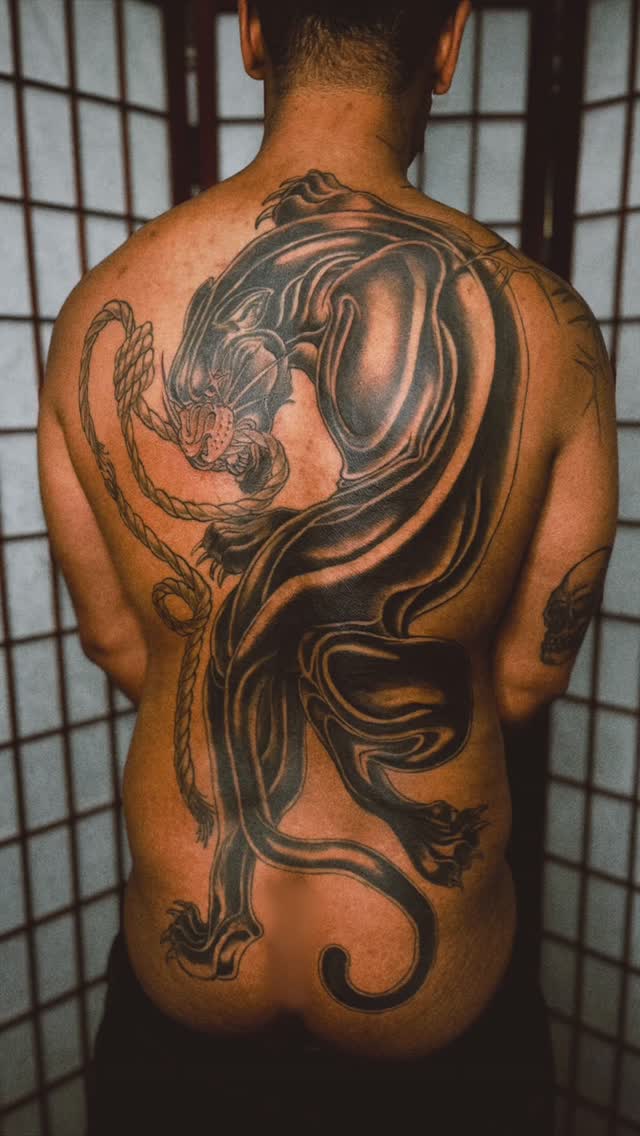 Dynamic blackwork dragon coils across a sculpted back