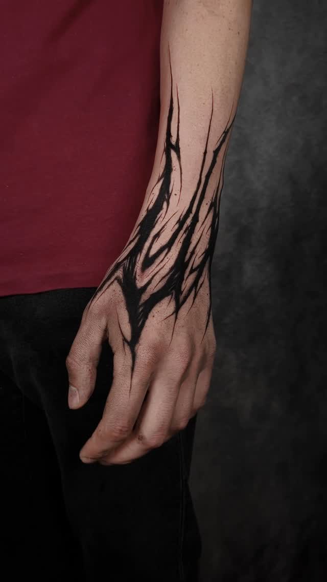 Bold black abstract branches weave down the forearm.