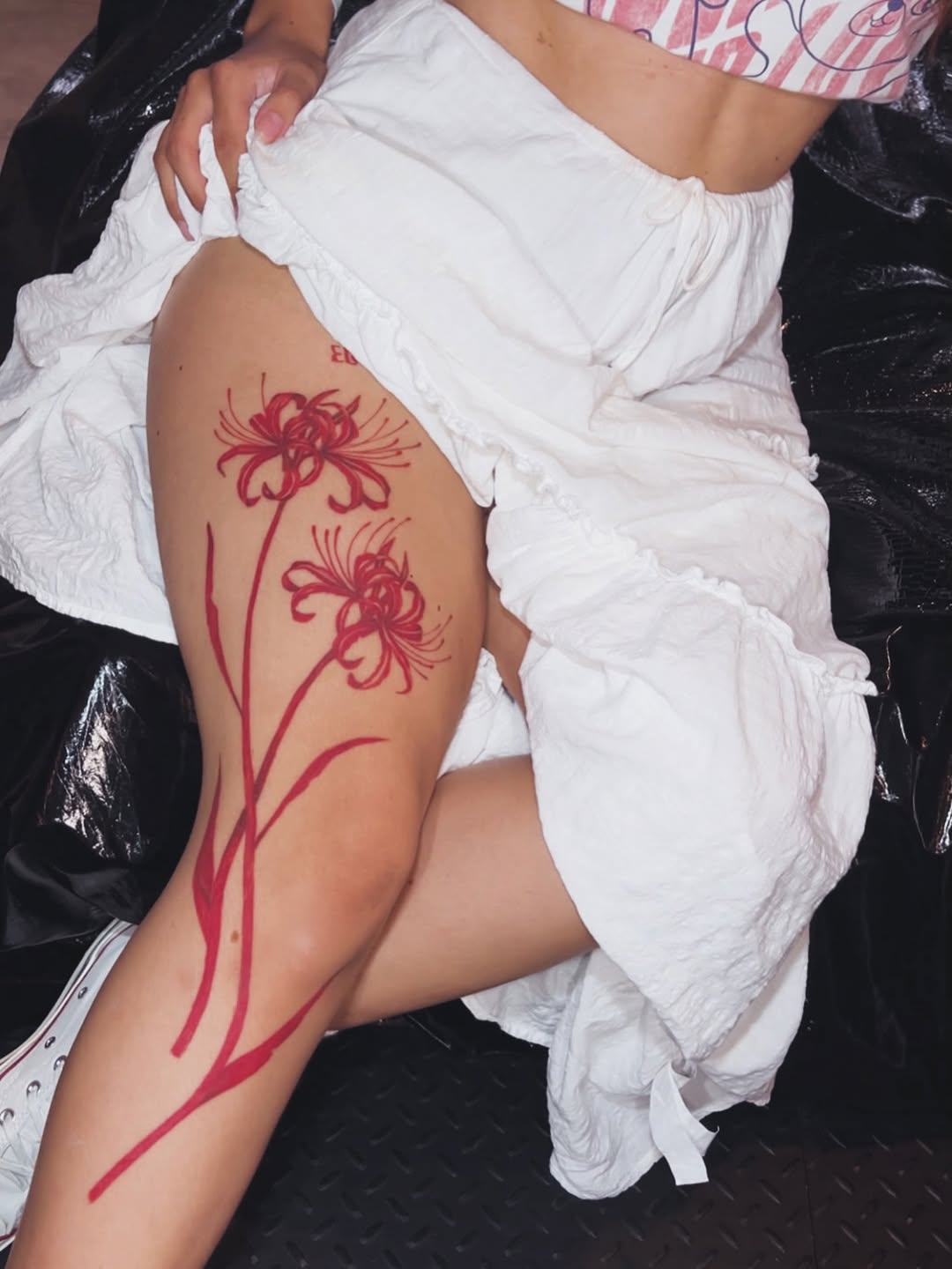 Red botanical floral linework wrapping the outer thigh