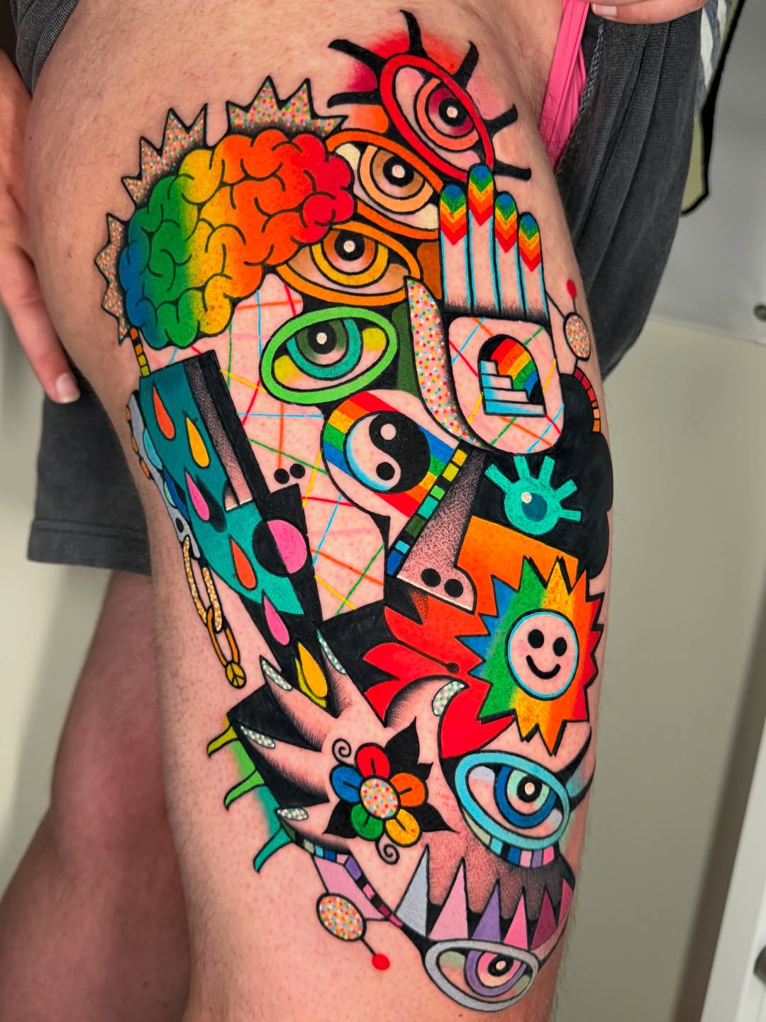 Bold, eye-filled neon dreamscape on thigh in pop-art style.