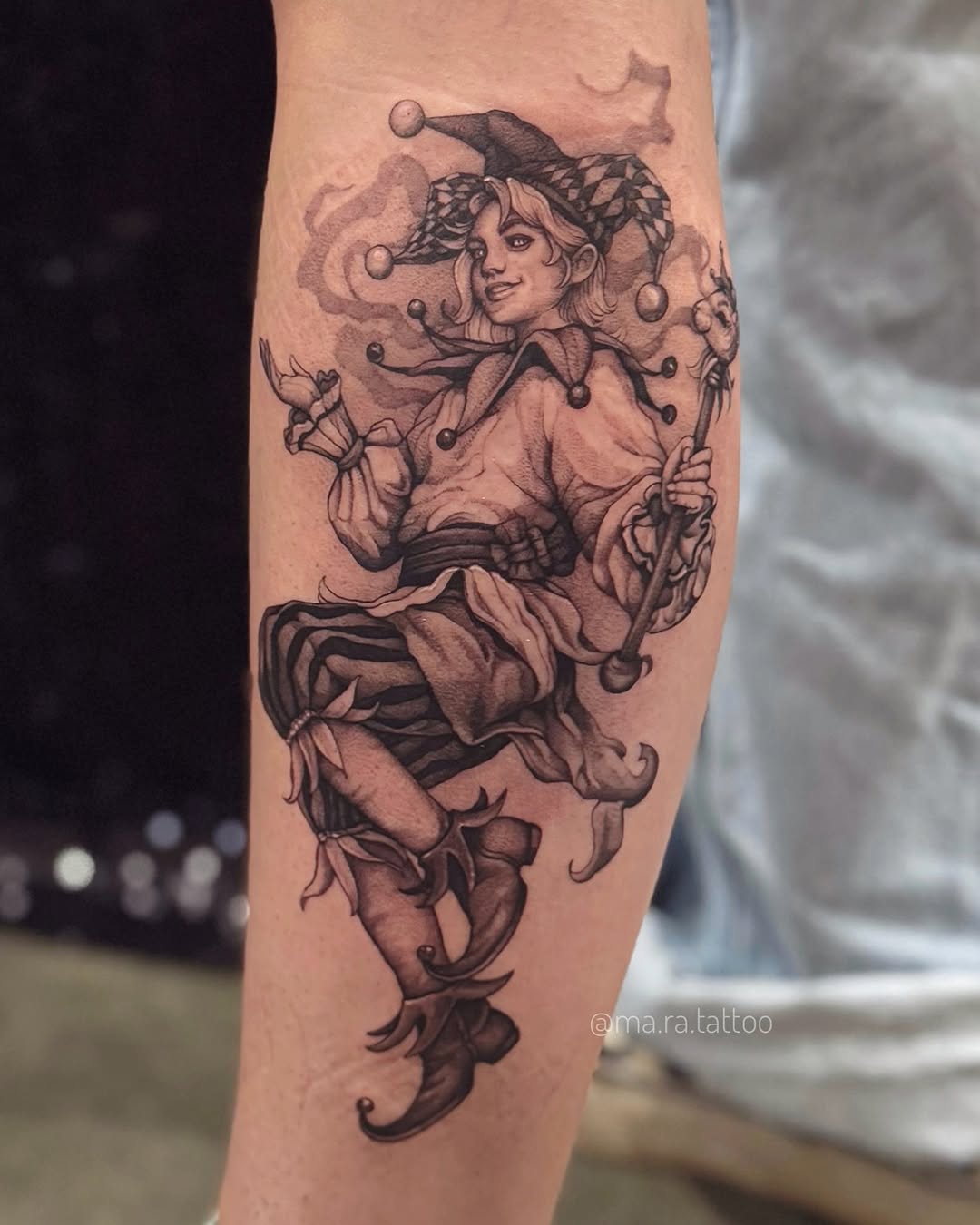 Intricate black-and-gray jester character on forearm.