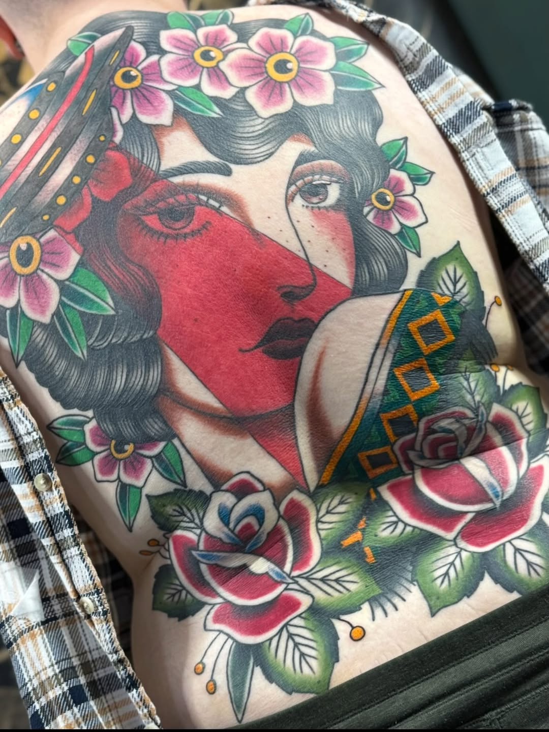 Vibrant neo-traditional back piece featuring a floral-framed woman