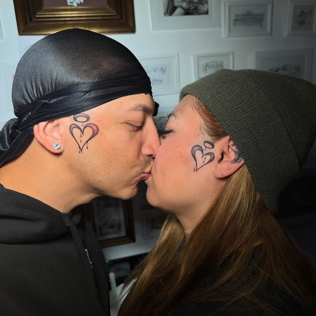 Twin minimalist heart tattoos on temples, intimate couple piece.