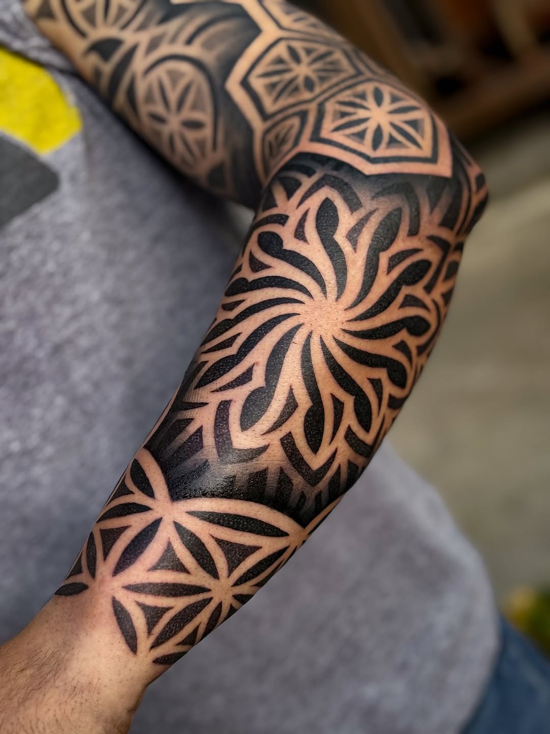 Bold blackwork geometric floral sleeve with starburst centers.