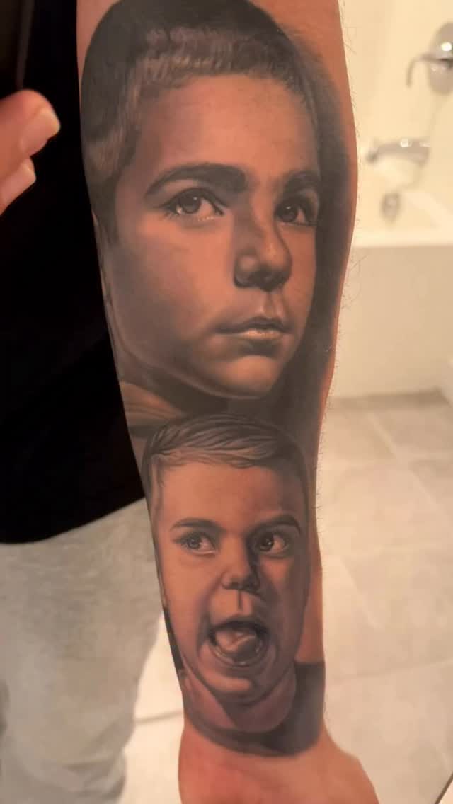Hyper-realistic grayscale baby portraits on forearm sleeve.