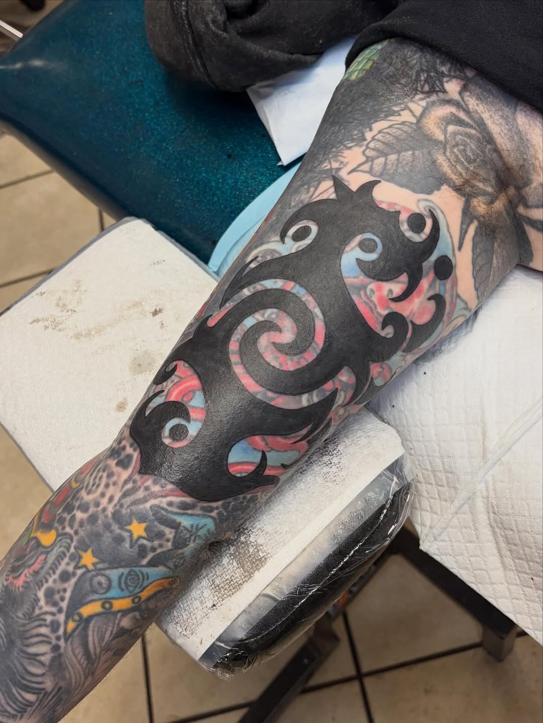 Bold blackwork swirl over watercolor pink-blue underlay