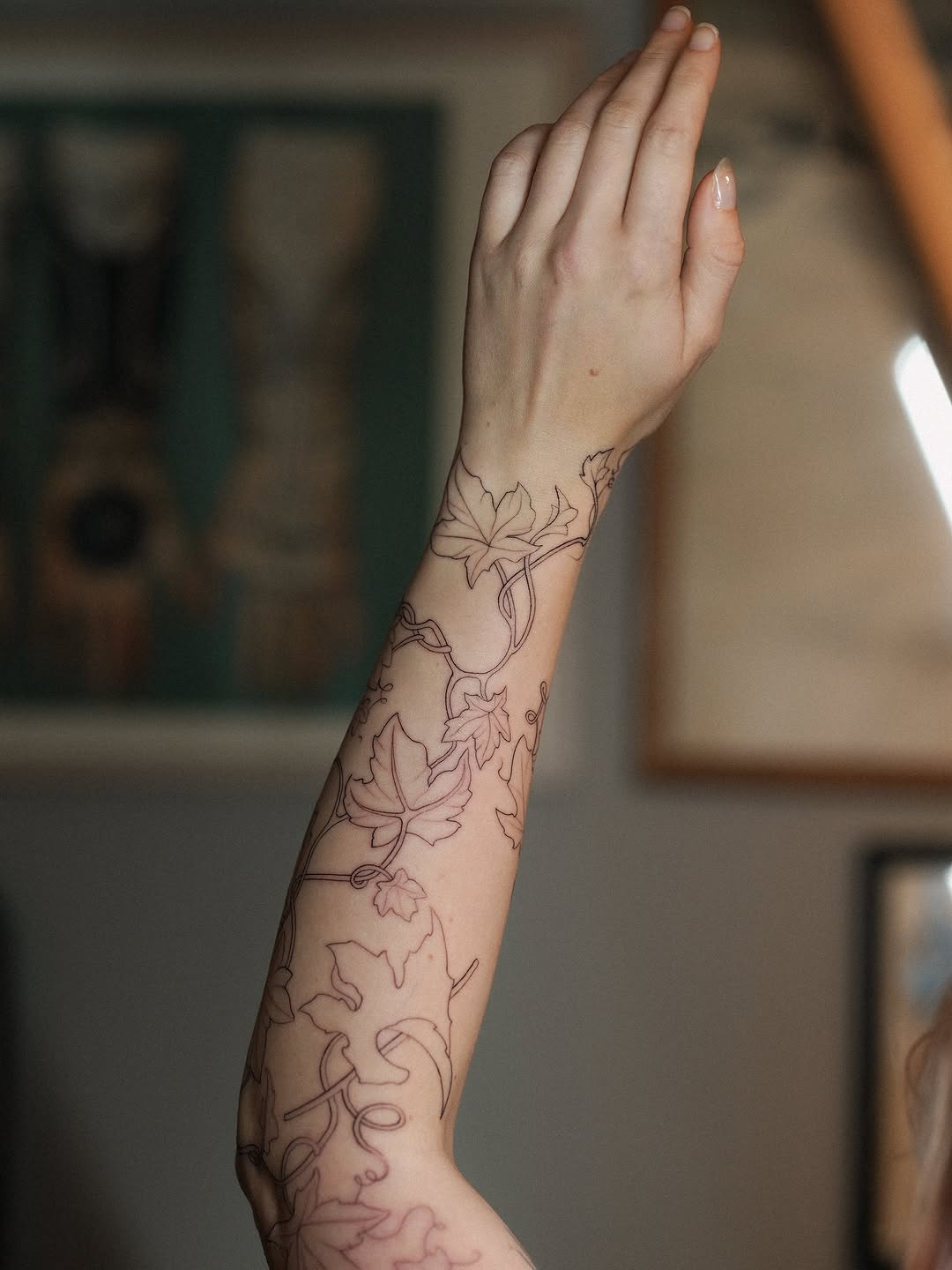 Delicate ivy vine wraps forearm in fine linework.