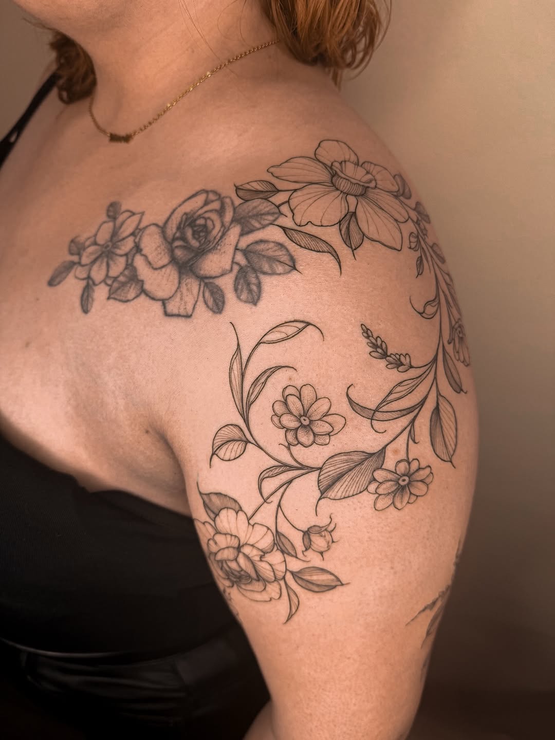 Delicate freehand floral garland wrapping shoulder in linework