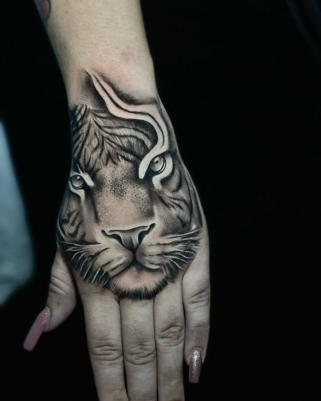 Monochrome tiger head on hand, dramatic shading.