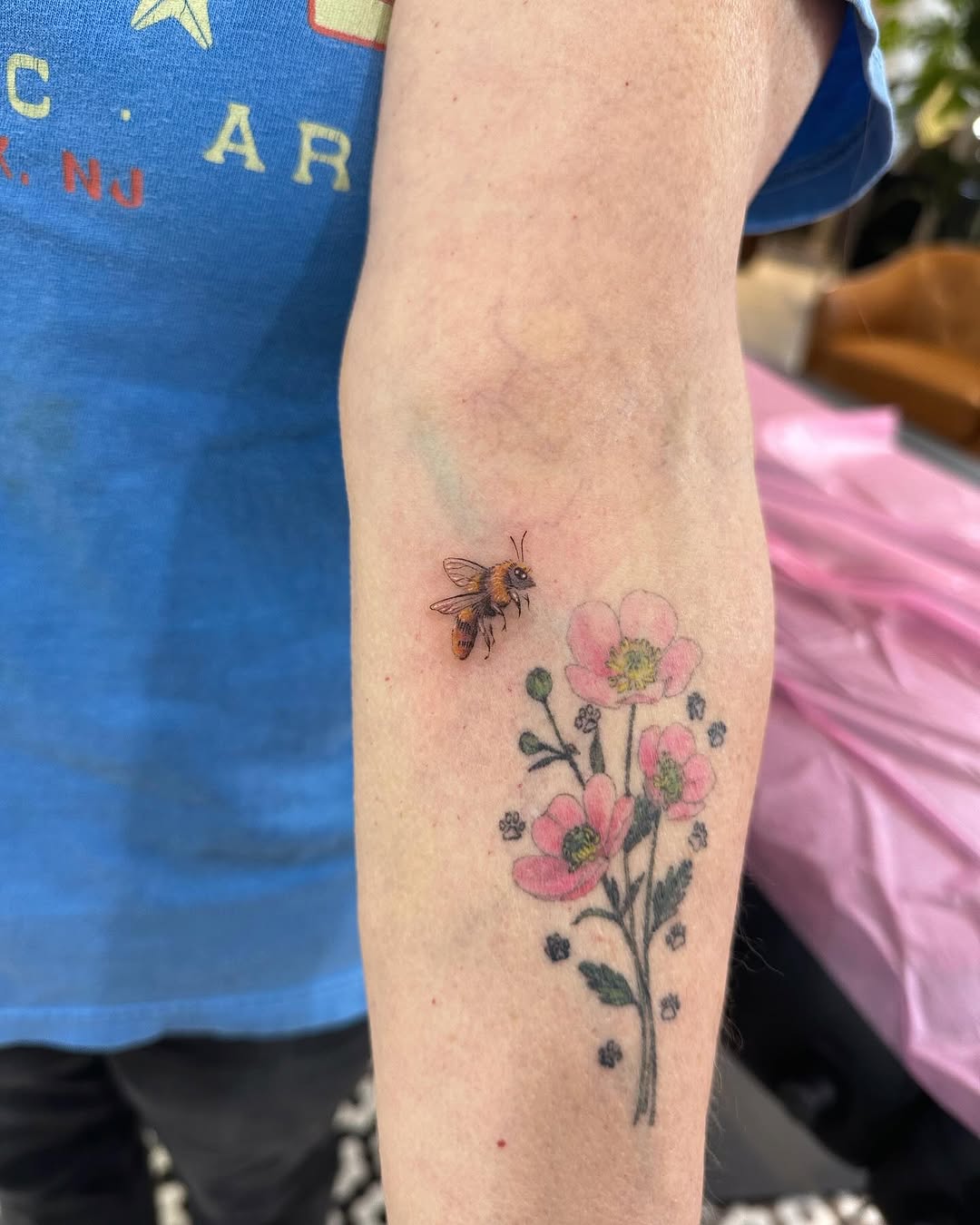 Delicate fine-line bee beside pastel pink flowers