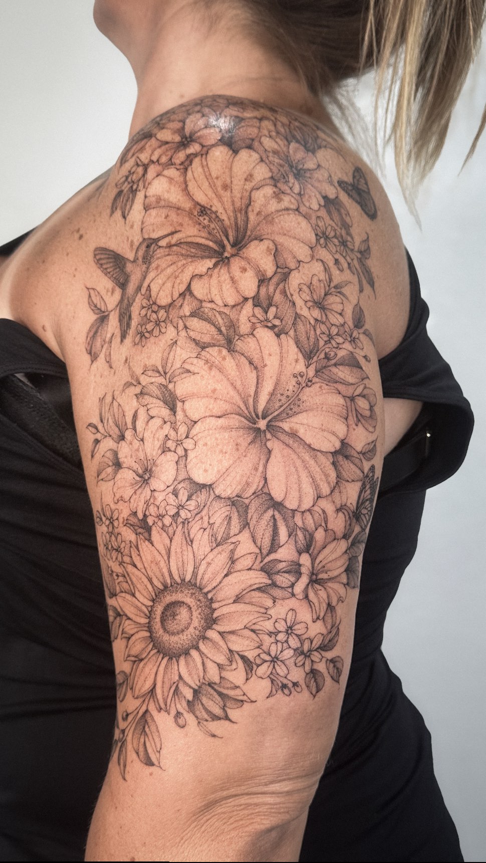 Lush floral half-sleeve with hibiscus, sunflowers, and hummingbird