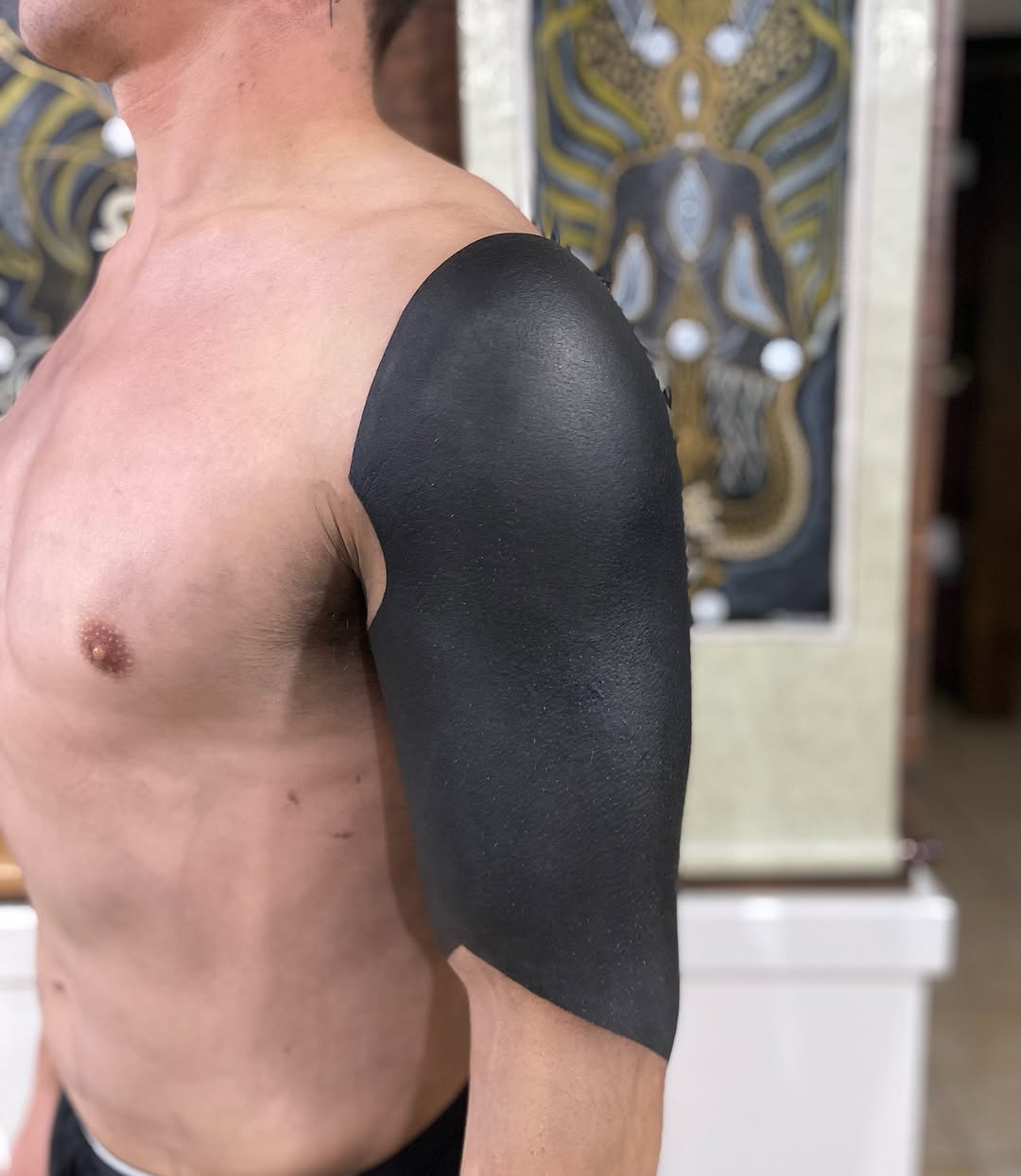 Bold, solid blackwork patch across shoulder and deltoid