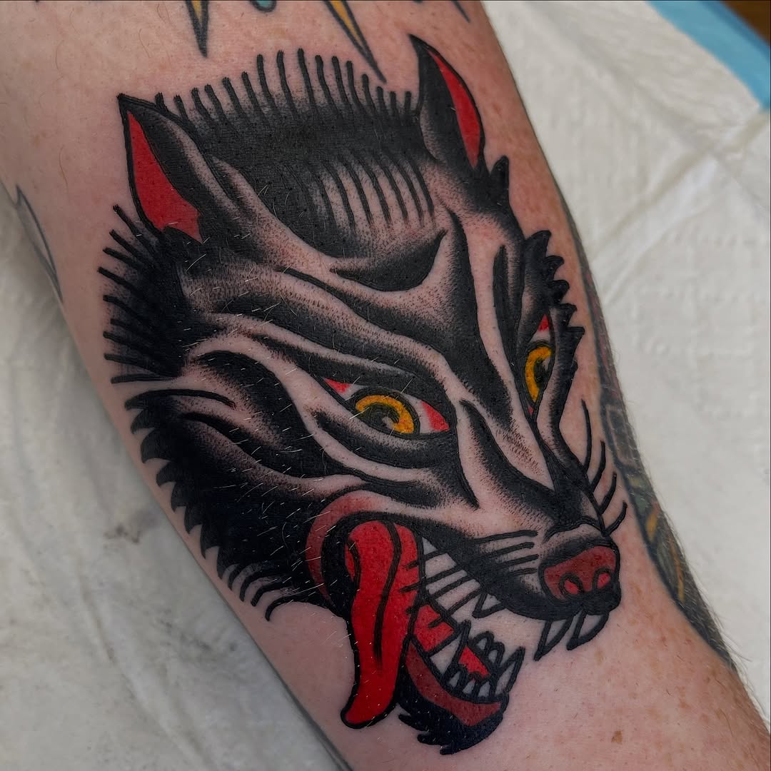 Bold blackwork wolf head with crimson tongue and yellow eyes