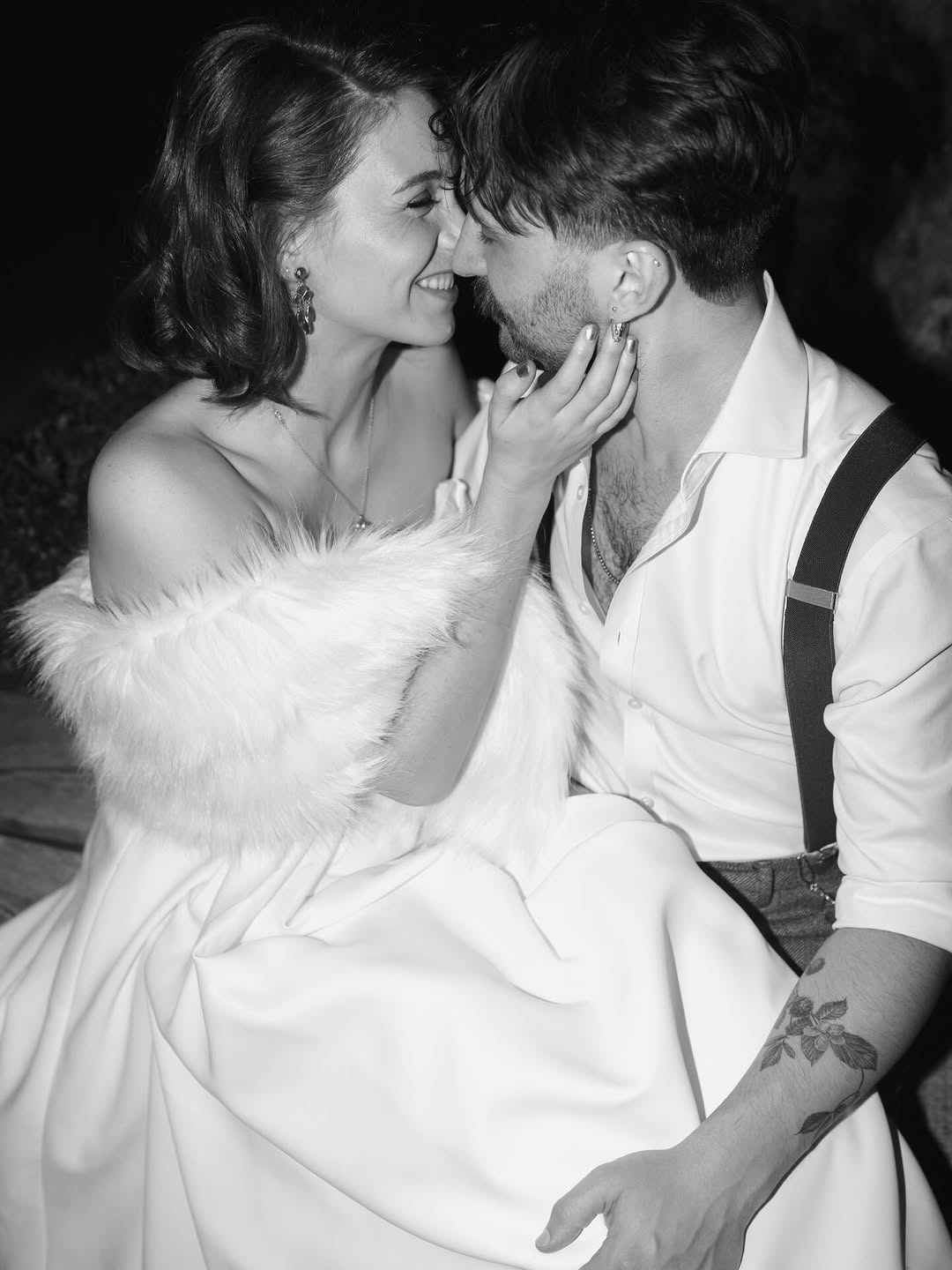 Tender wedding moment; floral forearm tattoo visible.