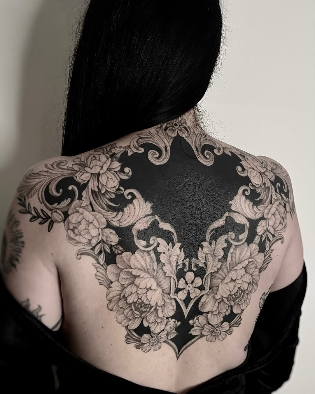 Intricate blackwork floral back piece with negative-space heart