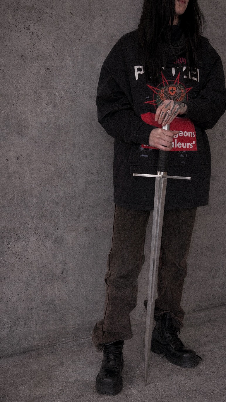 Bold blackwork hand tattoo peeks from under sleeve.